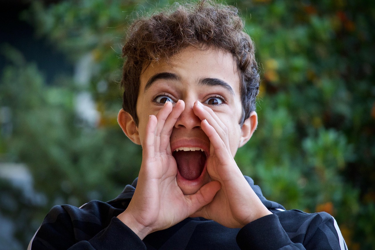 A person shouting toward the camera with hands cupped around their mouth